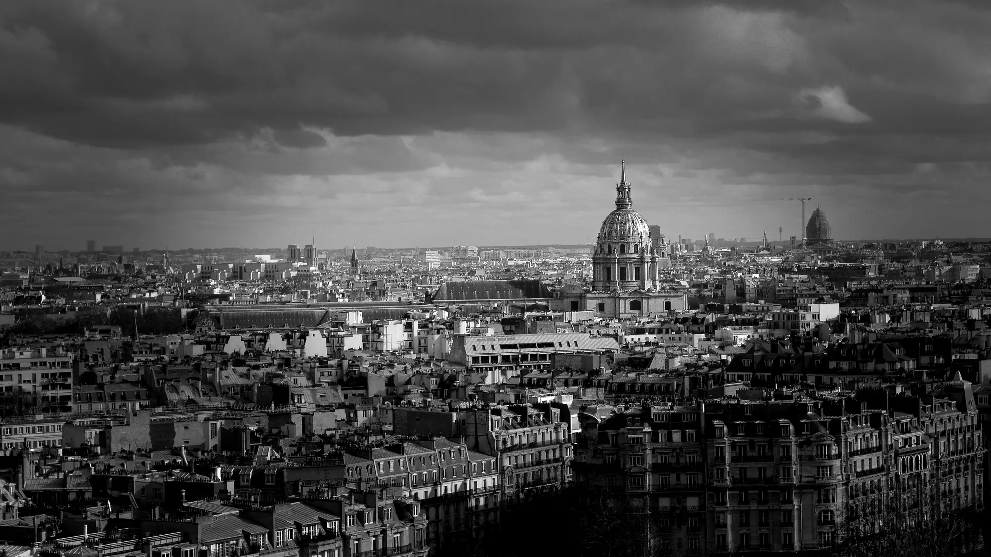 Paris rooftops under a heavy sky, with the dome of Les Invalides